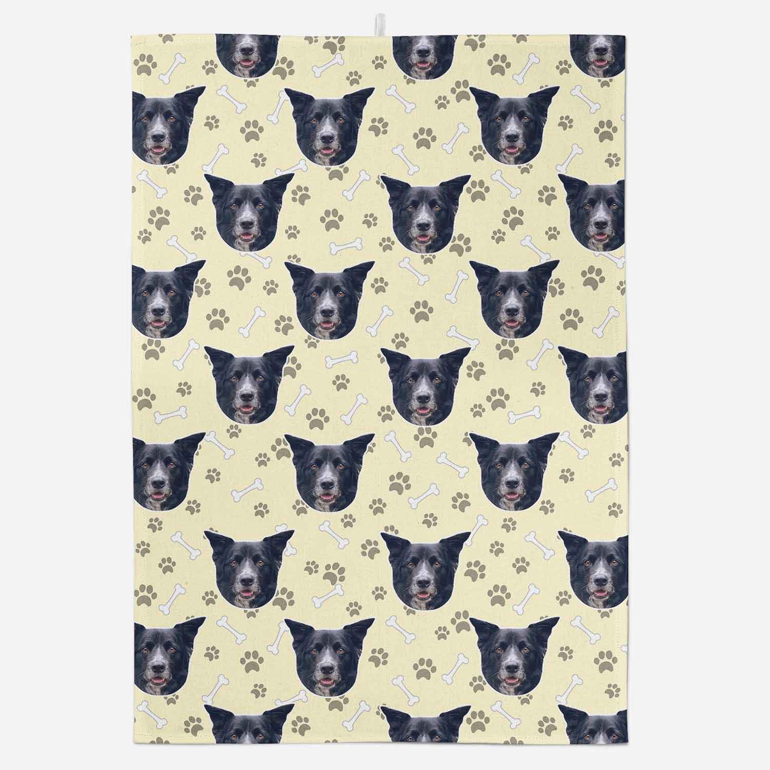 Patterned towel with black dog faces and paw prints on a light yellow background